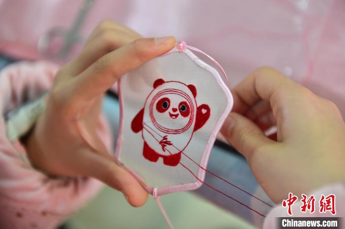 圖為一名小學(xué)生正在繡制2022年北京冬奧會(huì)吉祥物“冰墩墩”形象?！∮髟屏?攝