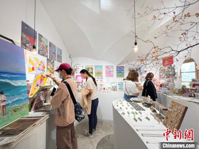 圖為藝術(shù)品商店內(nèi)，顧客挑選插畫作品?！＄婌?攝