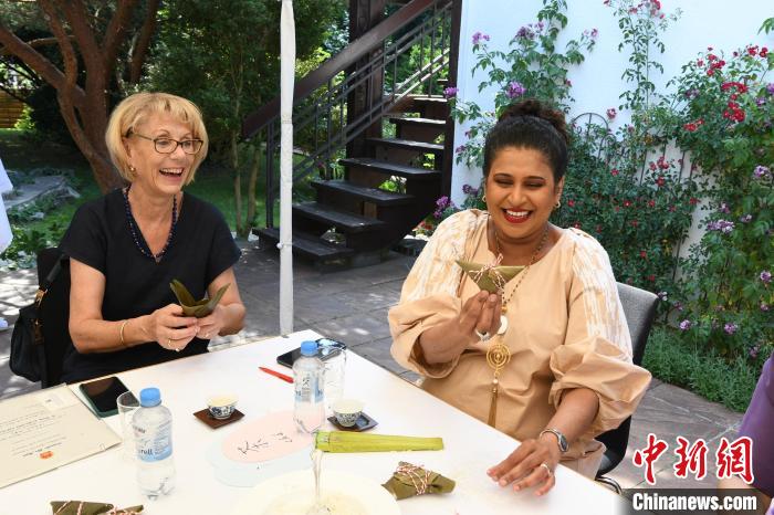 圖為嘉賓展示包粽子成果?！“亓种袊幕行墓﹫D。