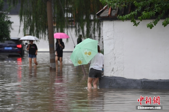 7月31日，市民行走在雨中的北京房山區(qū)瓦窯頭村。北京市氣象臺(tái)當(dāng)日10時(shí)發(fā)布分區(qū)域暴雨紅色預(yù)警信號(hào)。北京市水文總站發(fā)布洪水紅色預(yù)警，預(yù)計(jì)當(dāng)日12時(shí)至14時(shí)，房山區(qū)大石河流域?qū)⒊霈F(xiàn)紅色預(yù)警標(biāo)準(zhǔn)洪水。<a target='_blank' href='/'><p  align=
