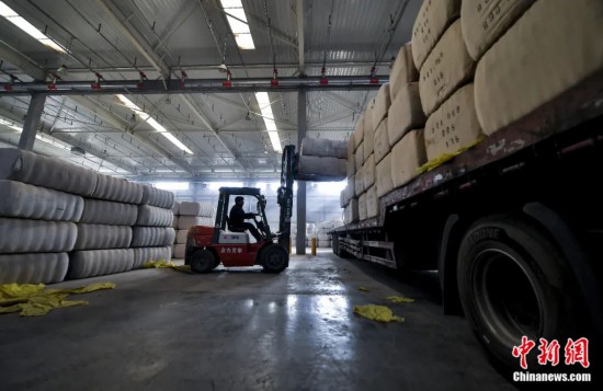 新疆喀什綜合保稅區(qū)，喀什啟路國際貿(mào)易有限公司的倉庫內(nèi)，工人正在裝載從塔吉克斯坦和烏茲別克斯坦進(jìn)口的棉花。劉新攝