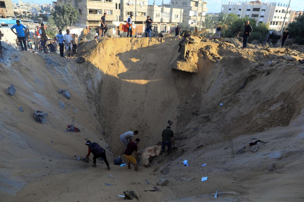 10月16日，在加沙地帶南部城市汗尤尼斯，人們在遭以色列襲擊后的建筑廢墟中救援傷者。 新華社發(fā)（亞西爾·庫迪 攝）