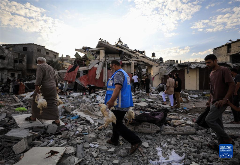 10月27日，在加沙地帶南部城市汗尤尼斯，人們經(jīng)過以軍襲擊后的房屋廢墟。