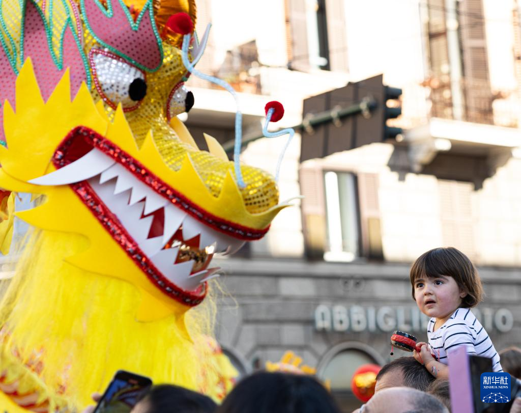 2月18日，在意大利羅馬，一名小朋友在彩妝巡游上觀看舞龍。新華社記者 李京 攝