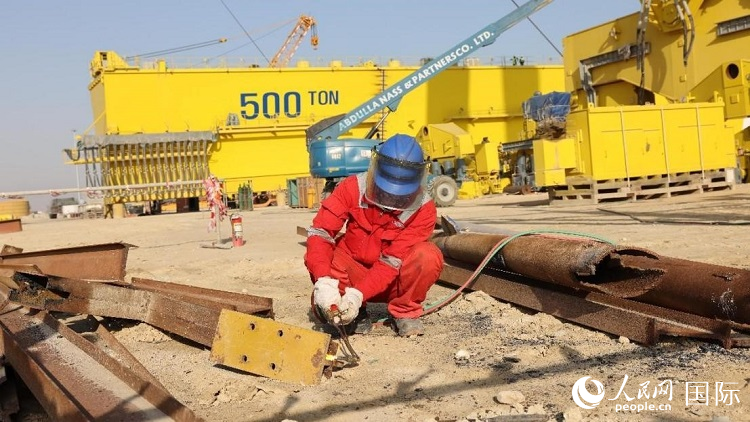 工人正在龍門吊吊裝現(xiàn)場切割金屬件。人民網(wǎng)記者管克江攝