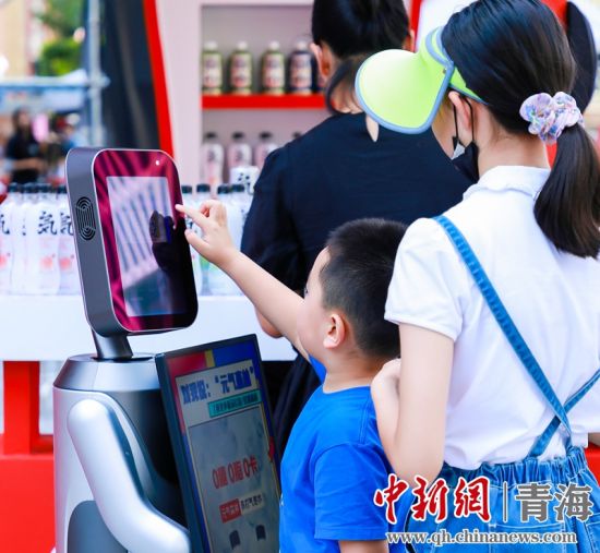 圖為一名小朋友正在和機器人“志愿者”進行互動。 沐聞 攝