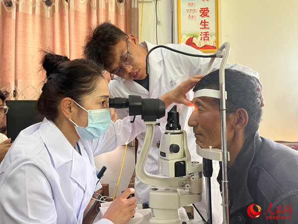 王紅英（左）和團(tuán)隊(duì)成員為達(dá)熱村村民檢查眼睛。人民網(wǎng)記者 杜燕飛攝