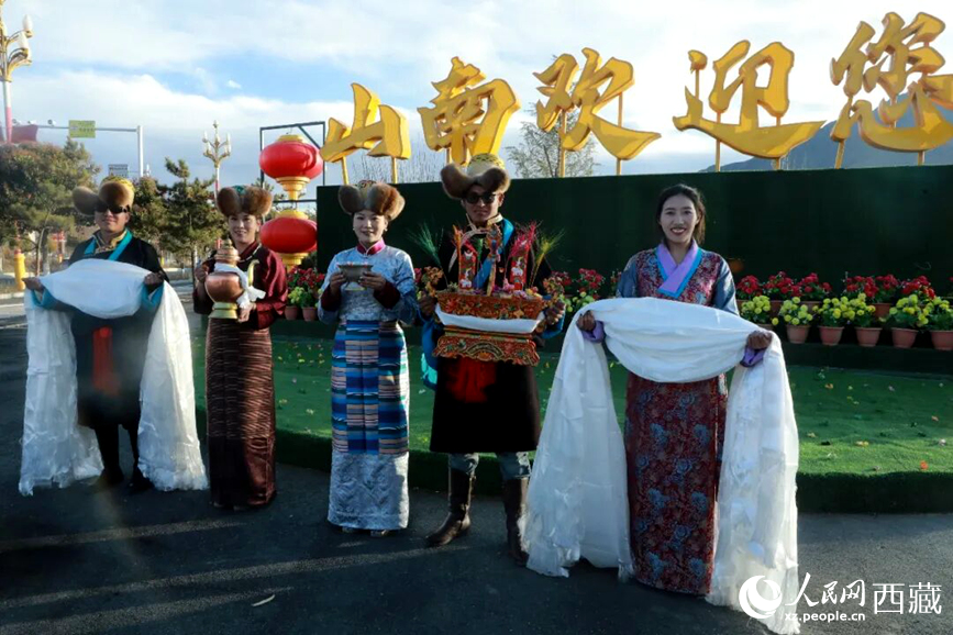 扎西曲登社區(qū)的居民在“山南歡迎您”標(biāo)志前，手持潔白哈達(dá)和切瑪，列隊(duì)迎接來自區(qū)內(nèi)外的游客，用最隆重的禮儀開啟一場沉浸式藏歷新年民俗體驗(yàn)之旅。人民網(wǎng)記者 吳雨仁攝