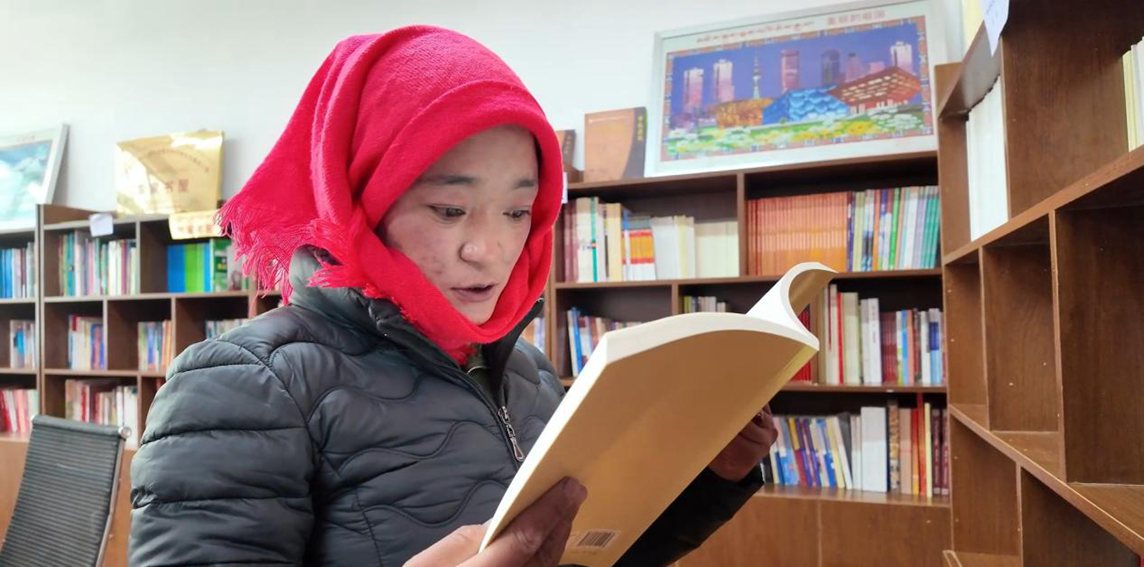 一名婦女正在認(rèn)真閱讀書籍。申扎縣融媒體中心供圖