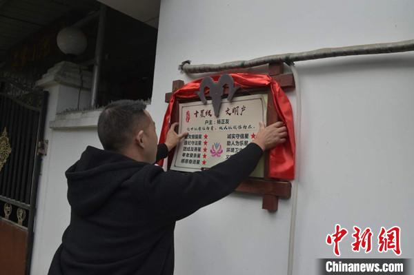 桂溪鎮(zhèn)渭溝村政府工作人員為“十星級(jí)文明戶”掛上牌匾。　楊勇 攝