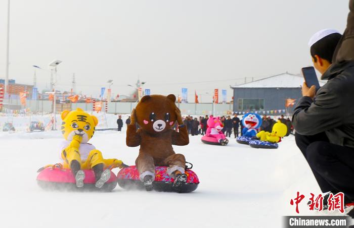 圖為臨夏市南龍鎮(zhèn)馬家莊村舉辦的鄉(xiāng)村文化旅游節(jié)上，游客穿著卡通服裝在體驗(yàn)雪上飛碟項(xiàng)目。近年來(lái)，臨夏州形成了“春賞花、夏避暑、秋摘果、冬玩雪”的全季節(jié)旅游產(chǎn)品體系。(資料圖) 高展 攝