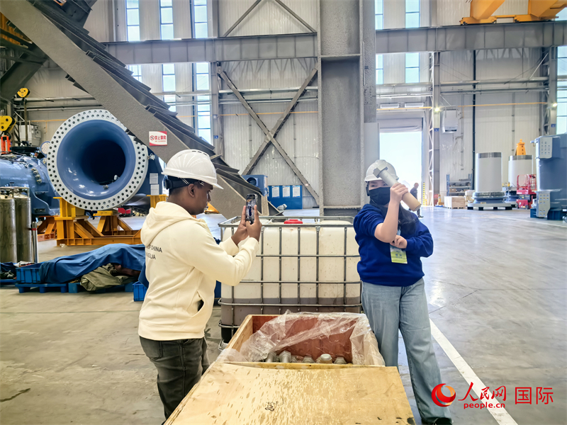 外媒記者掂量廠房內(nèi)的巨型螺栓。人民網(wǎng) 楊春燕攝