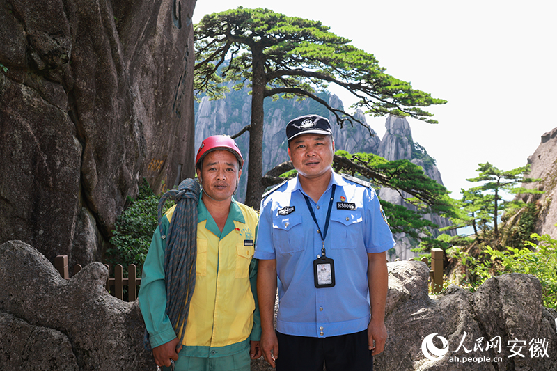 全國道德模范李培生（左）和胡曉春在迎客松前合影。人民網(wǎng)記者 張俊攝