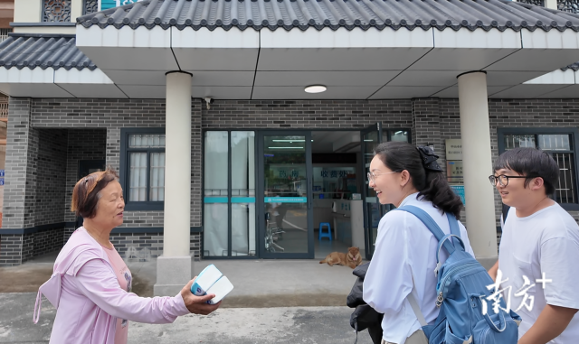 公共服務(wù)組成員王櫻潔（中）和張龍（右）在崖口村衛(wèi)生室前跟村民打招呼。