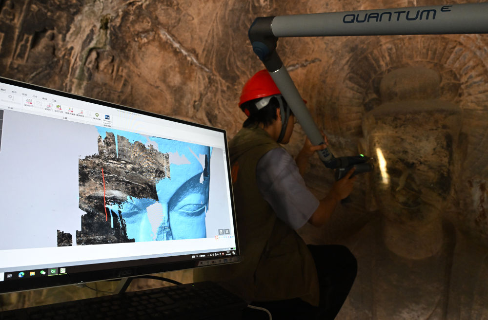 2025年4月9日，武漢大學(xué)文化遺產(chǎn)智能計(jì)算實(shí)驗(yàn)室團(tuán)隊(duì)成員在魏字洞使用關(guān)節(jié)臂掃描儀對(duì)佛像進(jìn)行數(shù)字化掃描。圖片來(lái)源新華社