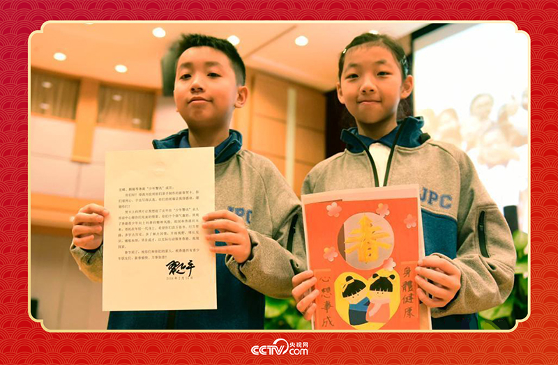 圖為香港“少年警訊”成員郭宏晞（左）展示習主席回信、羅顥凝（右）展示送給習主席的賀卡并合影。