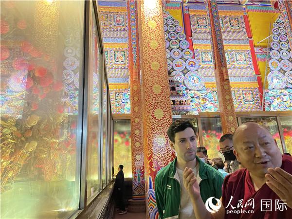 7月25日，省級(jí)非物質(zhì)文化遺產(chǎn)項(xiàng)目塔爾寺酥油花的代表性傳承人朋措堅(jiān)參（右）在塔爾寺酥油花館講解酥油花的制作過程。人民網(wǎng) 謝瑩攝