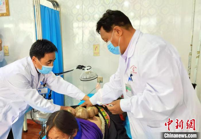 圖為看照加手把手帶徒弟加老(左一)進行拔罐療法。　張婧 攝