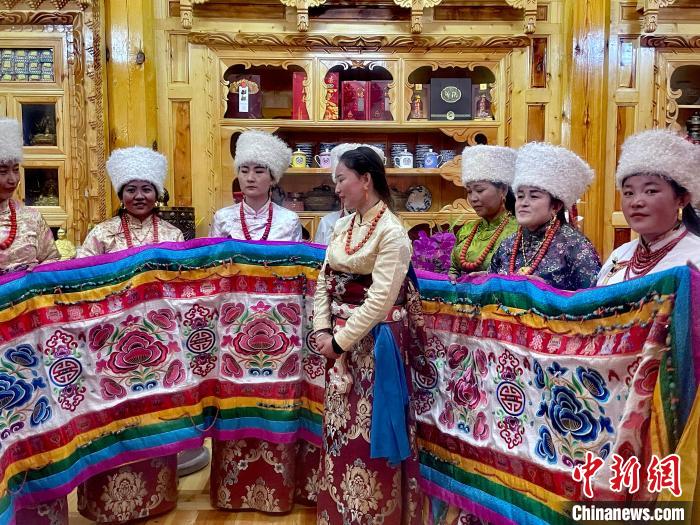 圖為女性展示村民自發(fā)繡制的“百米五彩哈達”?！±钣穹?攝