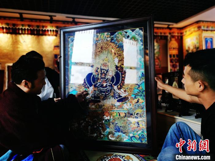 圖為久美尖措(左)與徒弟們展示唐卡作品?！?zhí)砀?攝