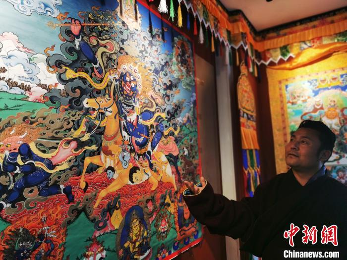 圖為久美尖措展示唐卡作品?！?zhí)砀?攝