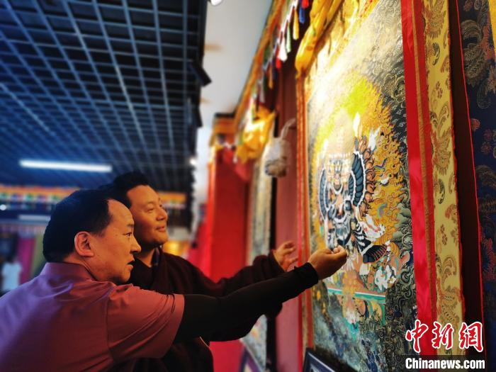 圖為久美尖措展示唐卡作品?！?zhí)砀?攝