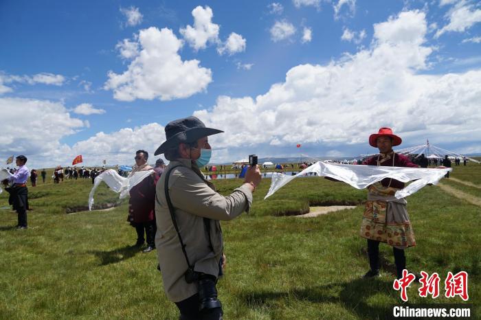 圖為一名外籍?dāng)z影師記錄當(dāng)?shù)夭刈鍤g迎儀式。　馬銘言 攝