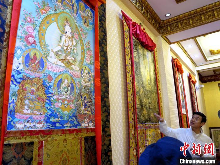圖為完德尖措展示熱貢龍樹畫苑內(nèi)的唐卡。　張?zhí)砀?攝