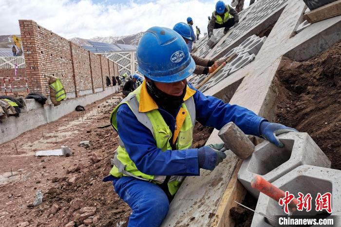 圖為光伏發(fā)電項(xiàng)目施工區(qū)工人在護(hù)坡鋪設(shè)空心磚。　李雋 攝