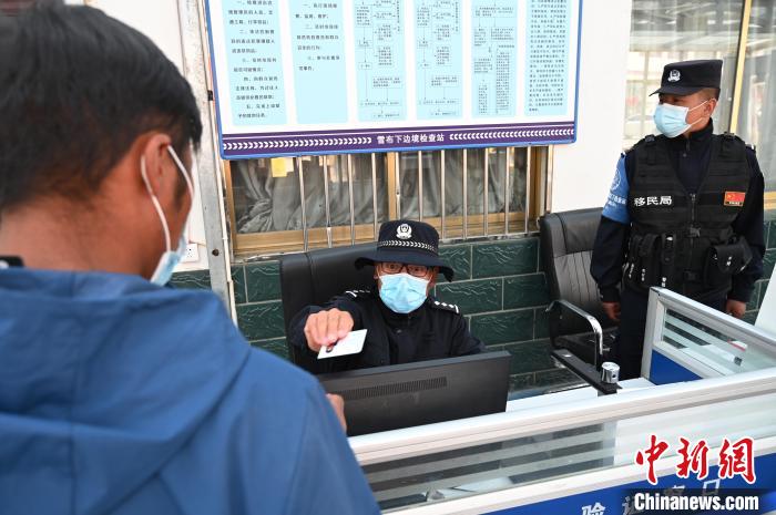 圖為移民管理警察登記完身份信息后將證件歸還給行人?！≮w朗 攝