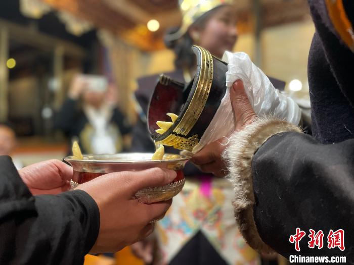 圖為主人在碗中斟滿青稞酒?！∪轿木?攝