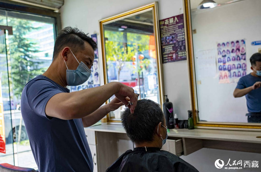 理發(fā)店老板為顧客理發(fā)。次仁羅布 攝