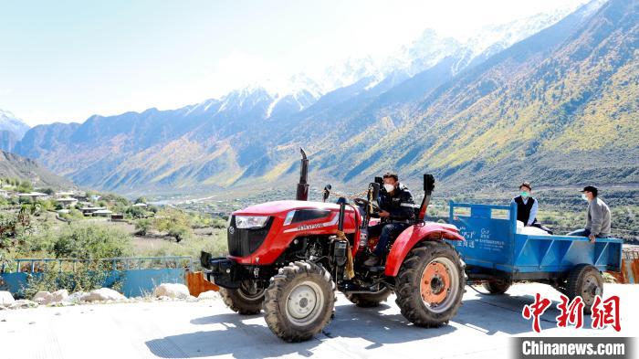 圖為工作人員將把加工完成的糌粑運(yùn)送至村民手中?！〖卫杩h融媒體中心供圖