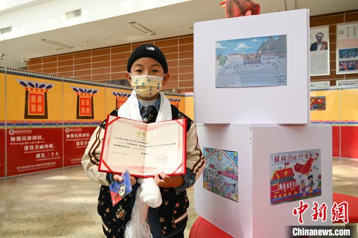 圖為一名獲獎學(xué)生與自己的繪畫作品合影。　趙朗 攝