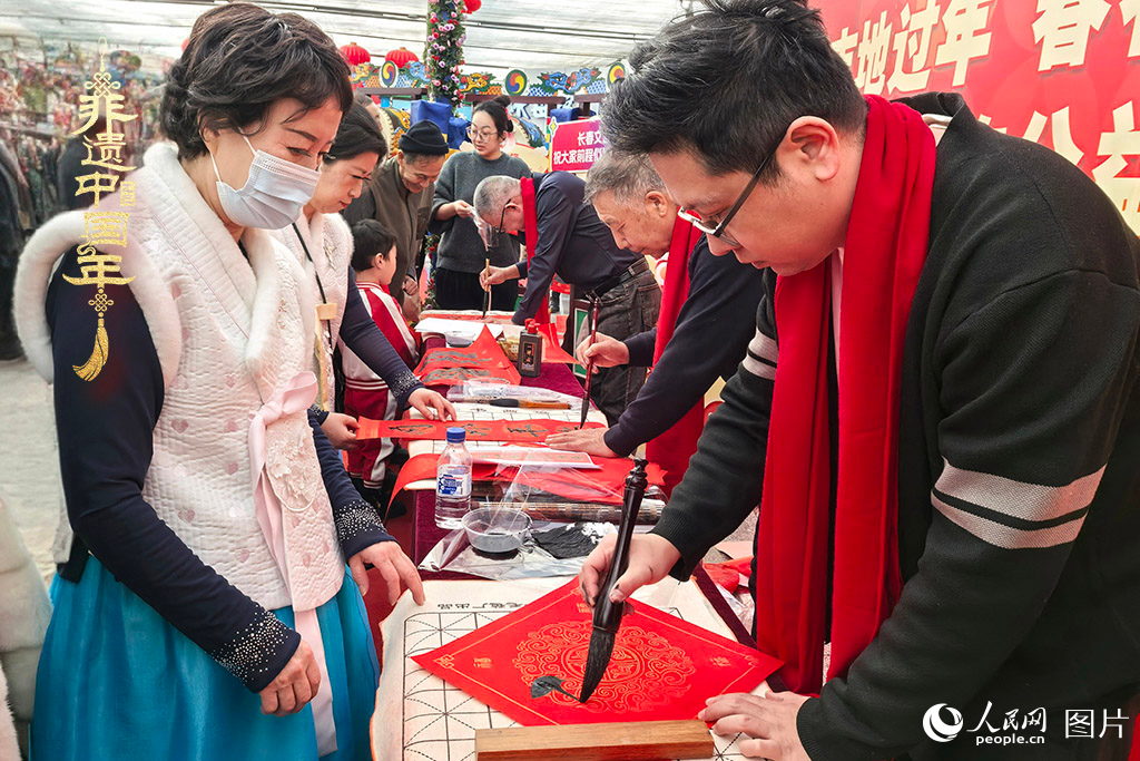 新春佳節(jié)之際，長春農(nóng)博園冬季展會火熱進行，展廳內(nèi)，書法家現(xiàn)場書寫“?！弊郑忻裼慰图娂娚锨坝航印案！?。人民網(wǎng)記者 王海躍攝
