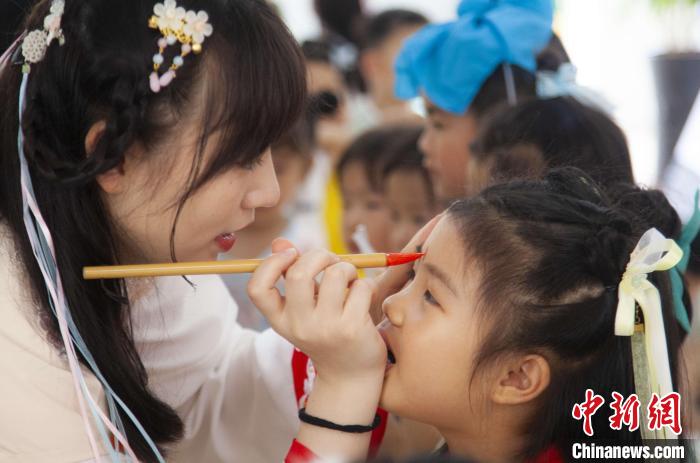 圖為老師在孩子們額頭上點(diǎn)上雄黃，驅(qū)邪辟禍?！《^生 攝