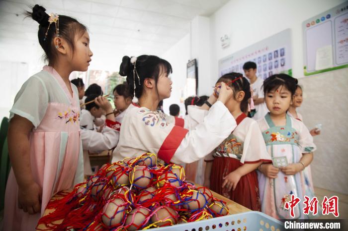 圖為幼兒園的老師們穿上漢服為小朋友們戴上彩蛋，寓意著幸福安康?！《^生 攝
